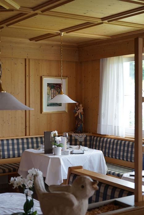 Eine gemütliche Sitzecke in einem Restaurant mit einer Eckbank, einem weiß gedeckten Tisch und einer Holzvertäfelung an den Wänden.